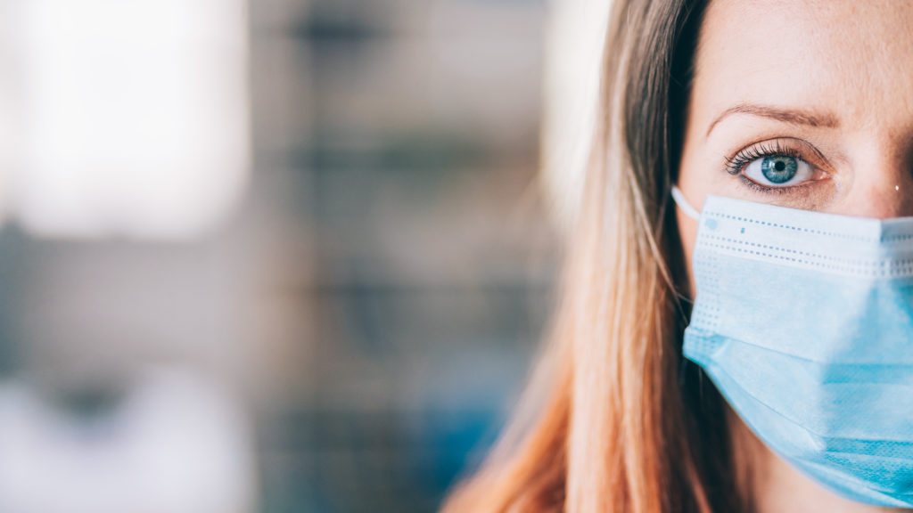 Woman wearing protective face mask in the office for safety and protection during COVID-19